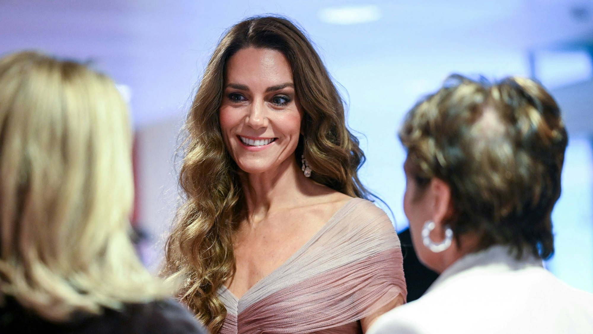 Kate Middleton lächelt mit zwei Personen