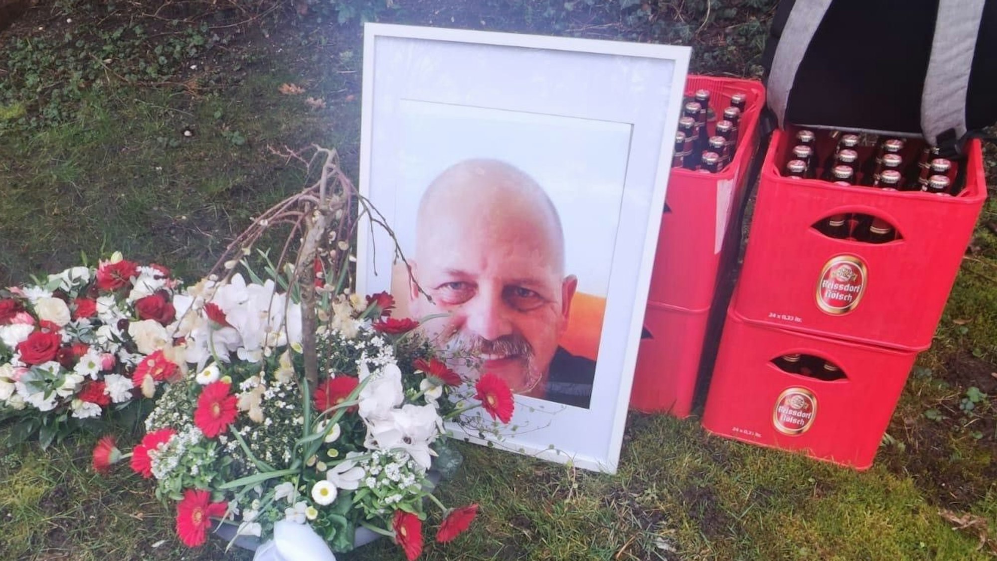 Das Foto eines Mannes lehnt an zwei gestapelten Kölsch-Kisten.