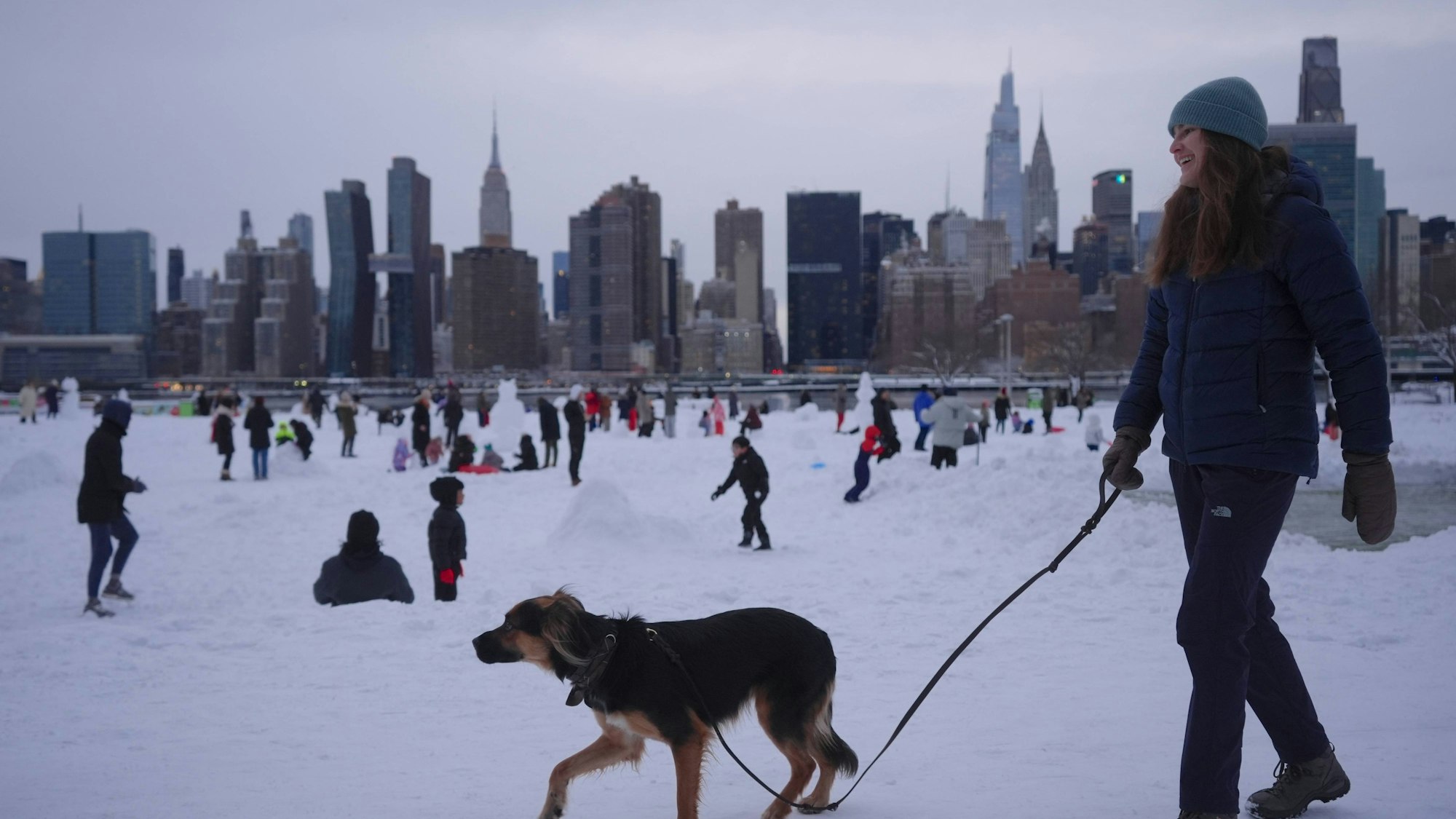 Frau und Hund mit Menschen und Stadt im Schnee