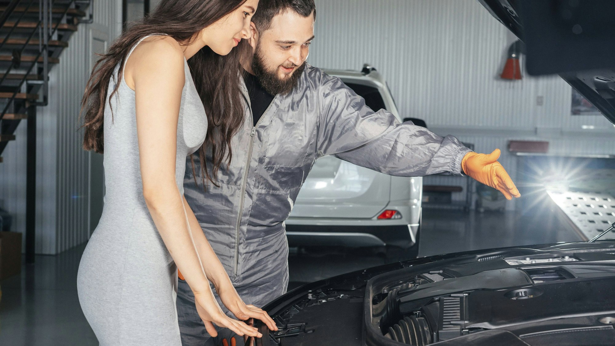 Automechaniker und Kundin vor offenem Automotor