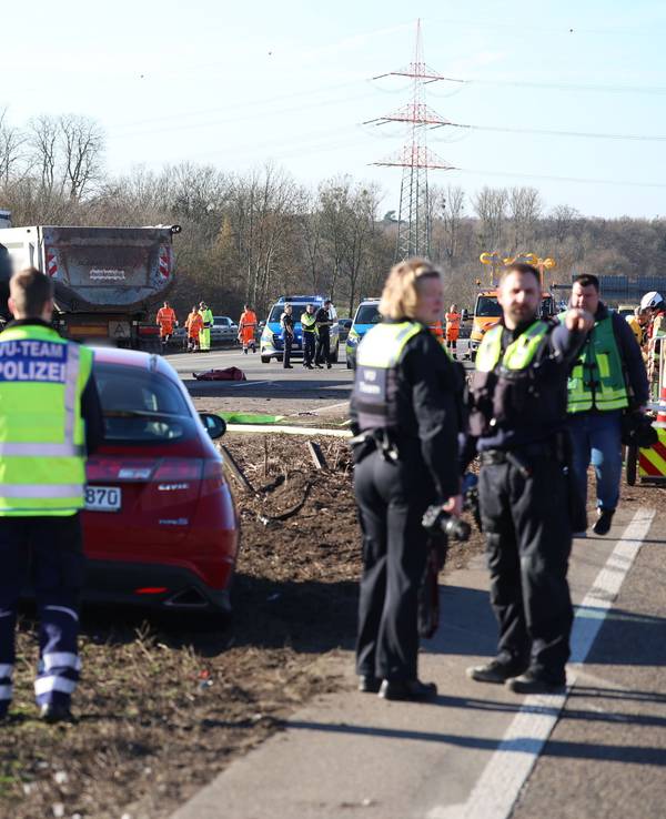 Einsatzkräfte stehen an einer Unfallstelle mit mehreren beschädigten Fahrzeugen.
