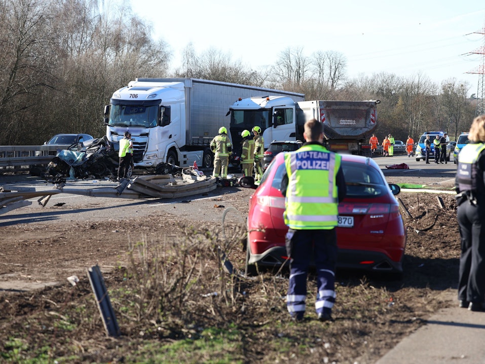 Einsatzkräfte stehen an einer Unfallstelle mit mehreren beschädigten Fahrzeugen.