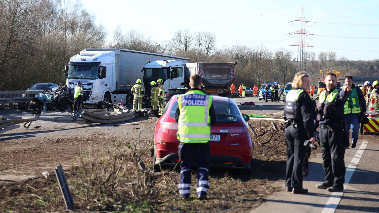 Einsatzkräfte stehen an einer Unfallstelle mit mehreren beschädigten Fahrzeugen.