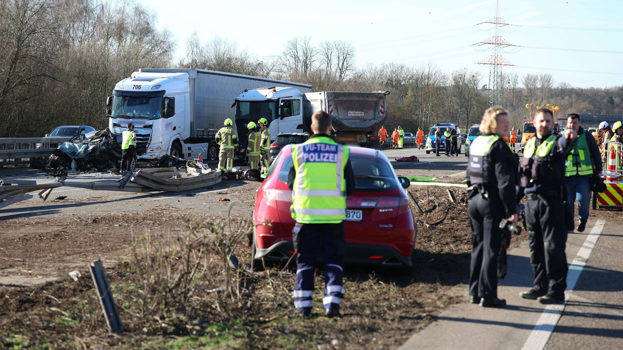 Einsatzkräfte stehen an einer Unfallstelle mit mehreren beschädigten Fahrzeugen.