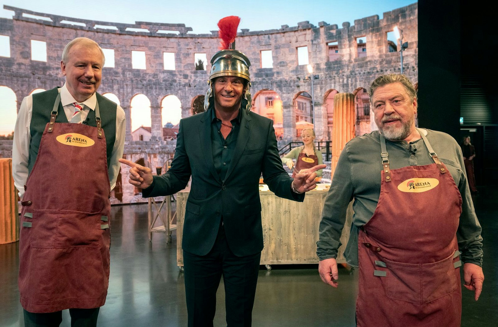 In der Arena von Showmoderator Konnowski (Stephan Luca, Mitte) wollen Wolfgang (Ludger Pistor, links) und Günther (Armin Rohde) ihre Geschäftsidee präsentieren. (Bild: WDR/Bavaria Fiction/Thomas Kost)