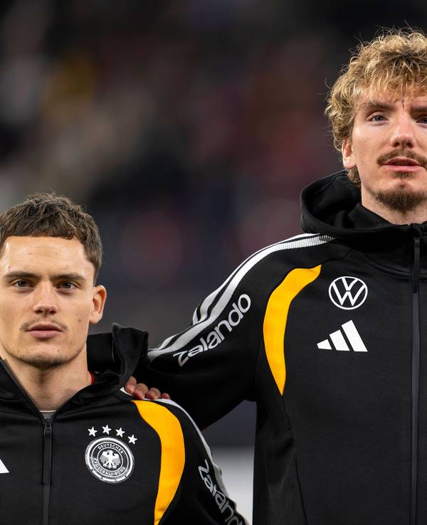Florian Wirtz, Nick Woltemade und Aleksandar Pavlovic in schwarzer Trainingsjacke bei der Hymne.
