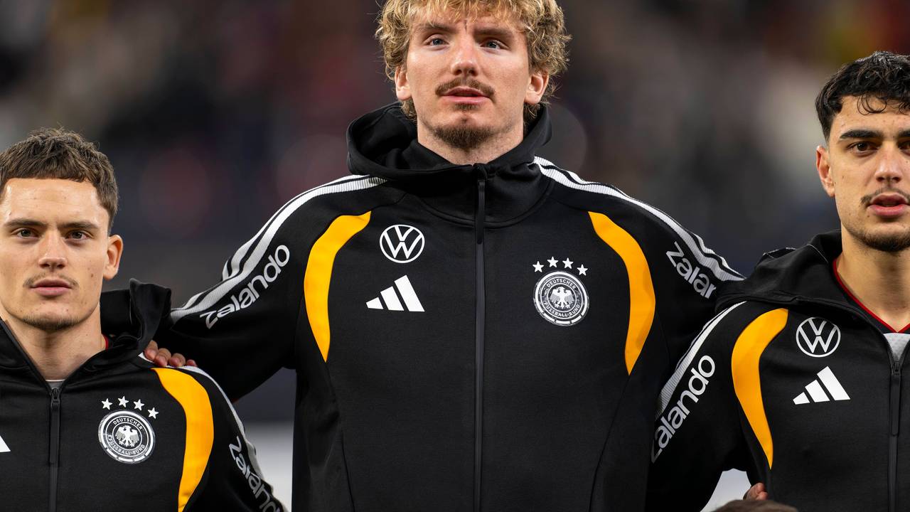 Florian Wirtz, Nick Woltemade und Aleksandar Pavlovic in schwarzer Trainingsjacke bei der Hymne.