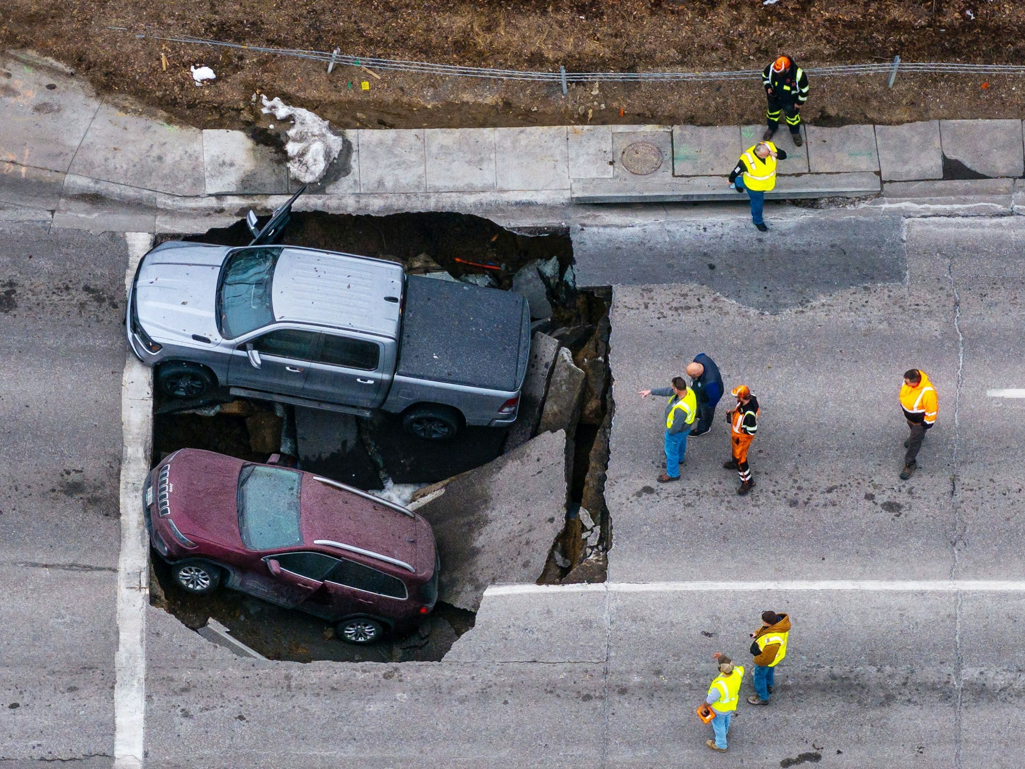 Beamte begutachten einen Unfall, bei dem zwei Fahrzeuge auf der Pacific Street östlich der 67th Street in Omaha in ein Sinkloch gestürzt sind.
