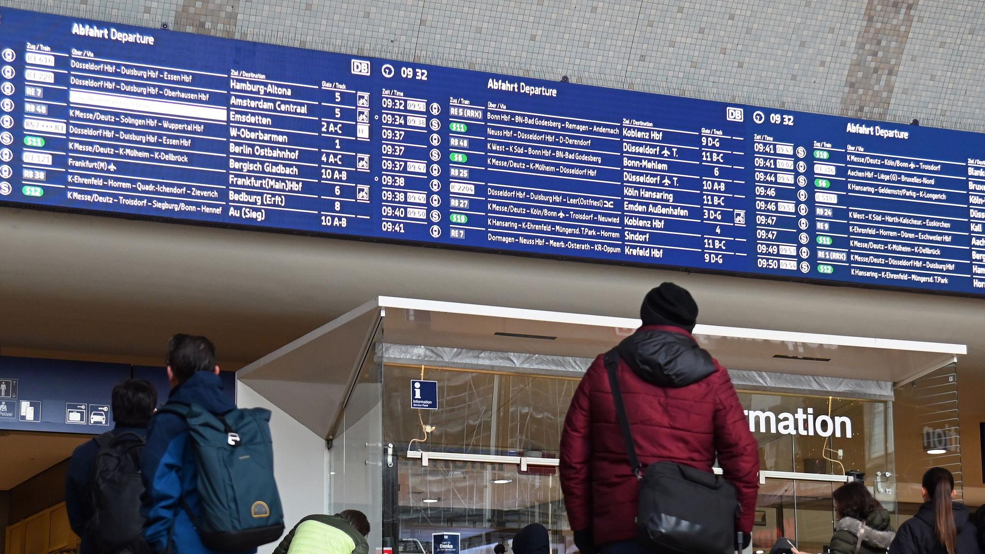 Reisende schauen auf die Anzeigetafel im Kölner Hauptbahnhof.