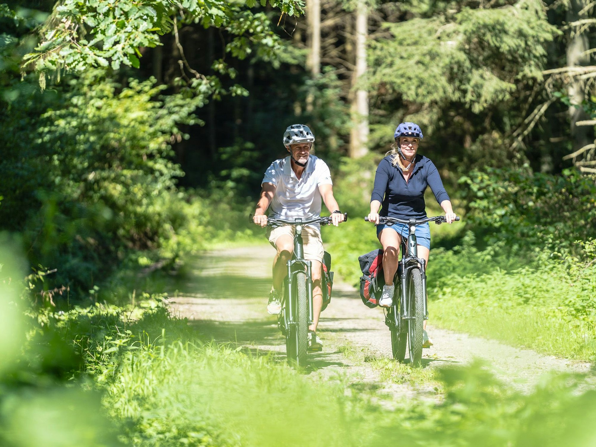 Ein Mann und eine Frau fahren mit Fahrrädern über einen Waldweg