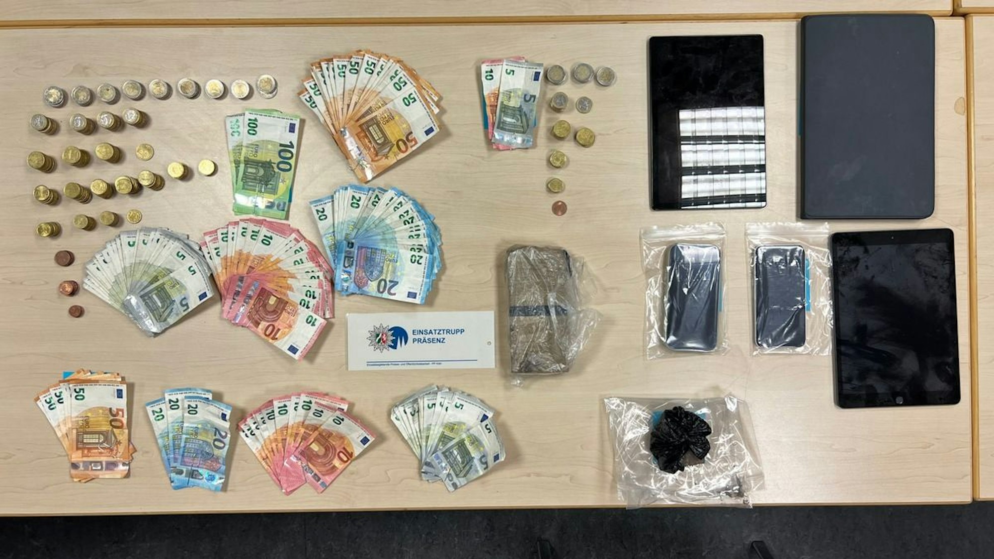 Auf einem Tisch ausgebreitete Asservaten: Drogen, Bargeld und Feinwaagen.