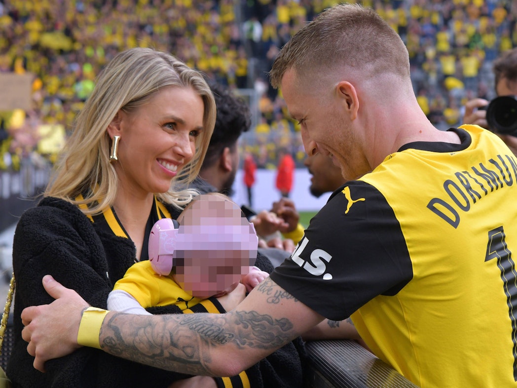 Scarlett Gartmann und Marco Reus umarmen sich mit Baby.