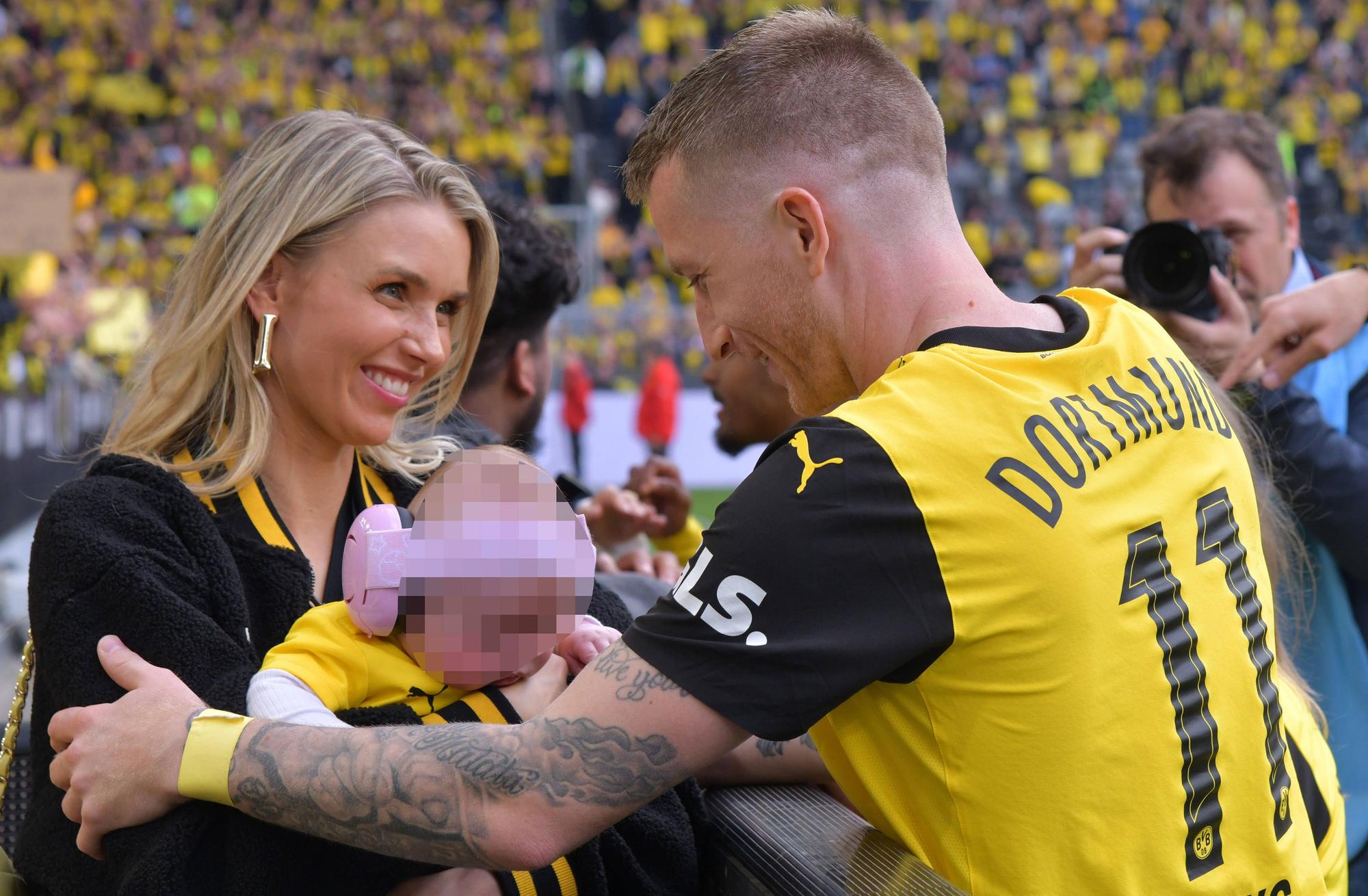 Scarlett Gartmann und Marco Reus umarmen sich mit Baby.
