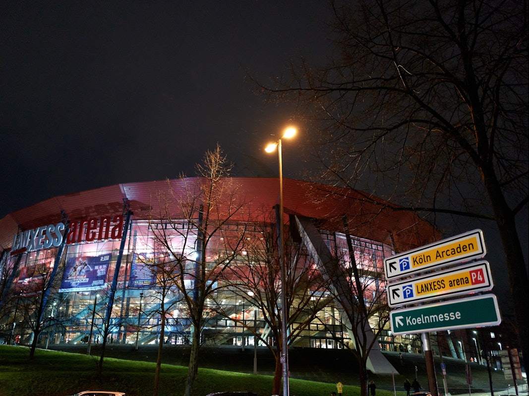 Parkschilder vor der beleuchteten Lanxess-Arena.