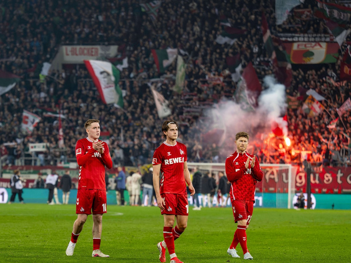 Isak Johannesson, Jakub Kaminski und Florian Kainz gehen nach Spielende in Augsburg mit langen Gesichtern in die Kurve zu den FC-Fans.