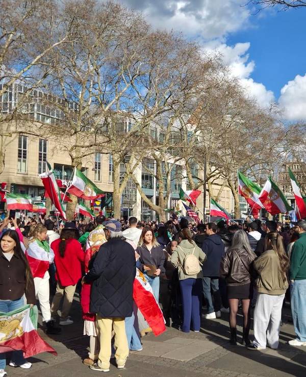 Menschen mit Iran-Flaggen drängen sich auf einem Platz.
