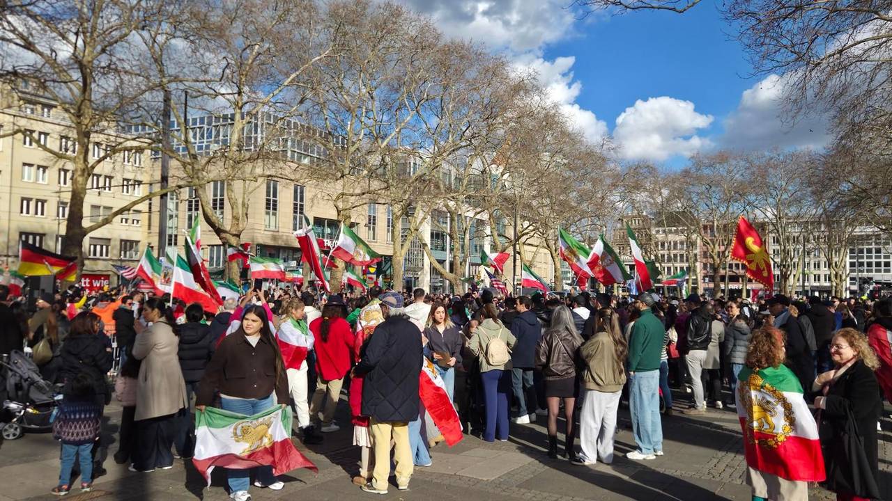 Menschen mit Iran-Flaggen drängen sich auf einem Platz.