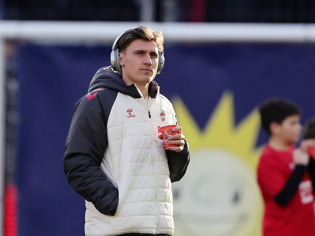 Alessio Castro-Montes (1. FC Köln) steht mit Kopfhörern auf dem Platz.