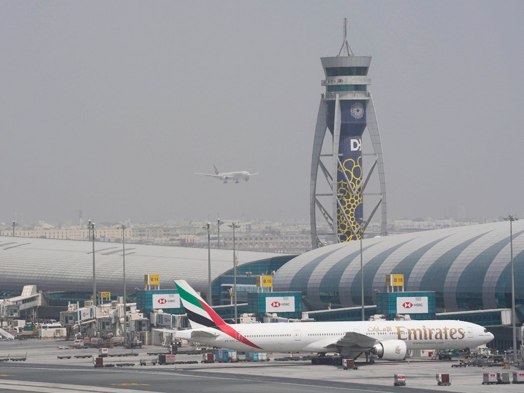 ARCHIV - 17.08.2022, Vereinigte Arabische Emirate, Dubai: ARCHIV - Eine Boeing 777 der Fluggesellschaft Emirates steht am Gate des internationalen Flughafens von Dubai, während sich eine andere Maschine auf die Landung auf der Startbahn vorbereitet. (zu dpa: «Angriff Irans? Verletzte nach «Vorfall» am Flughafen Dubai») Foto: Jon Gambrell/AP/dpa +++ dpa-Bildfunk +++
