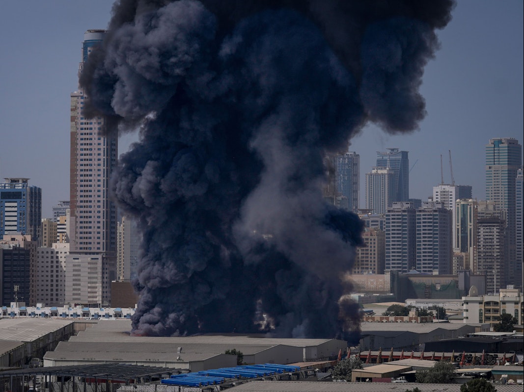 Eine schwarze Rauchwolke steigt aus einem Lagerhaus in den Himmel.