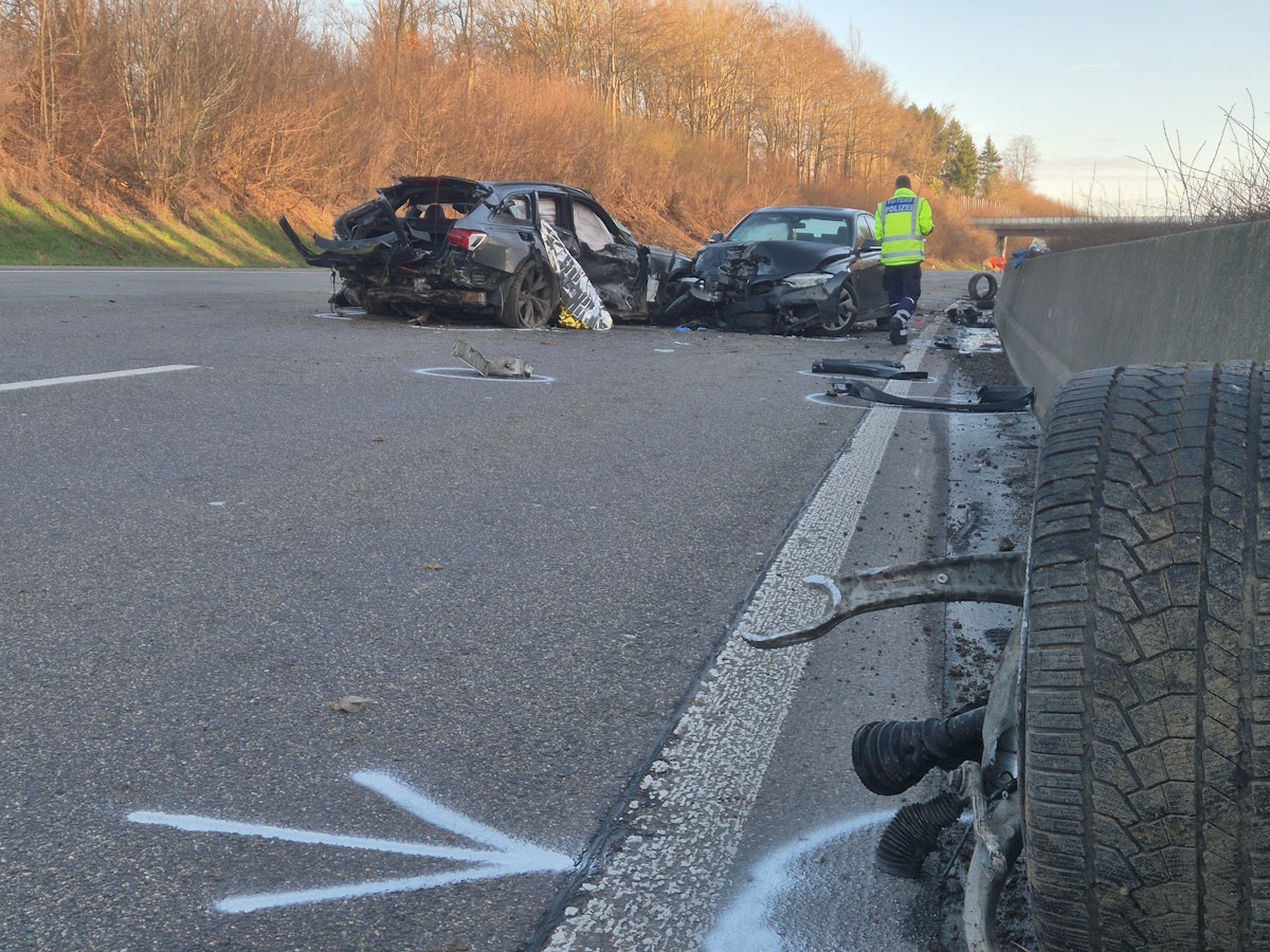 Ein Polizist geht nach einem Unfall auf der A1 an den verunglückten Fahrzeugen und zahlreichen Trümmerteilen entlang.