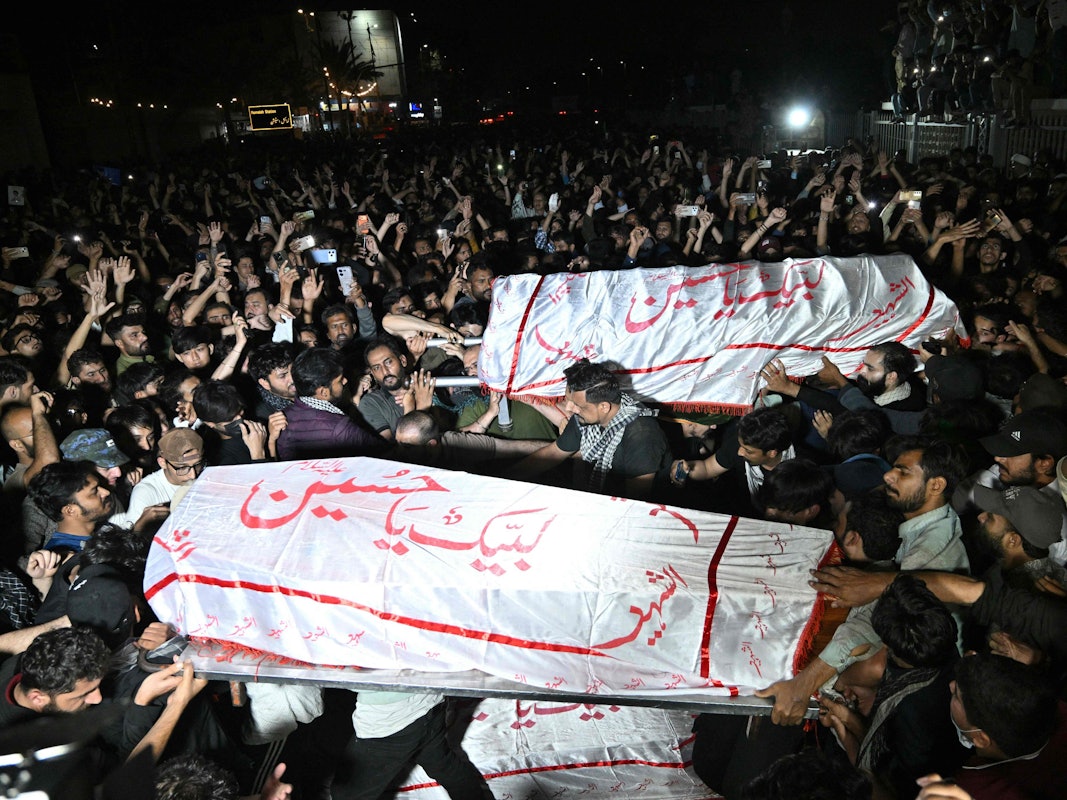 Menschen tragen Särge durch Menschenmassen.