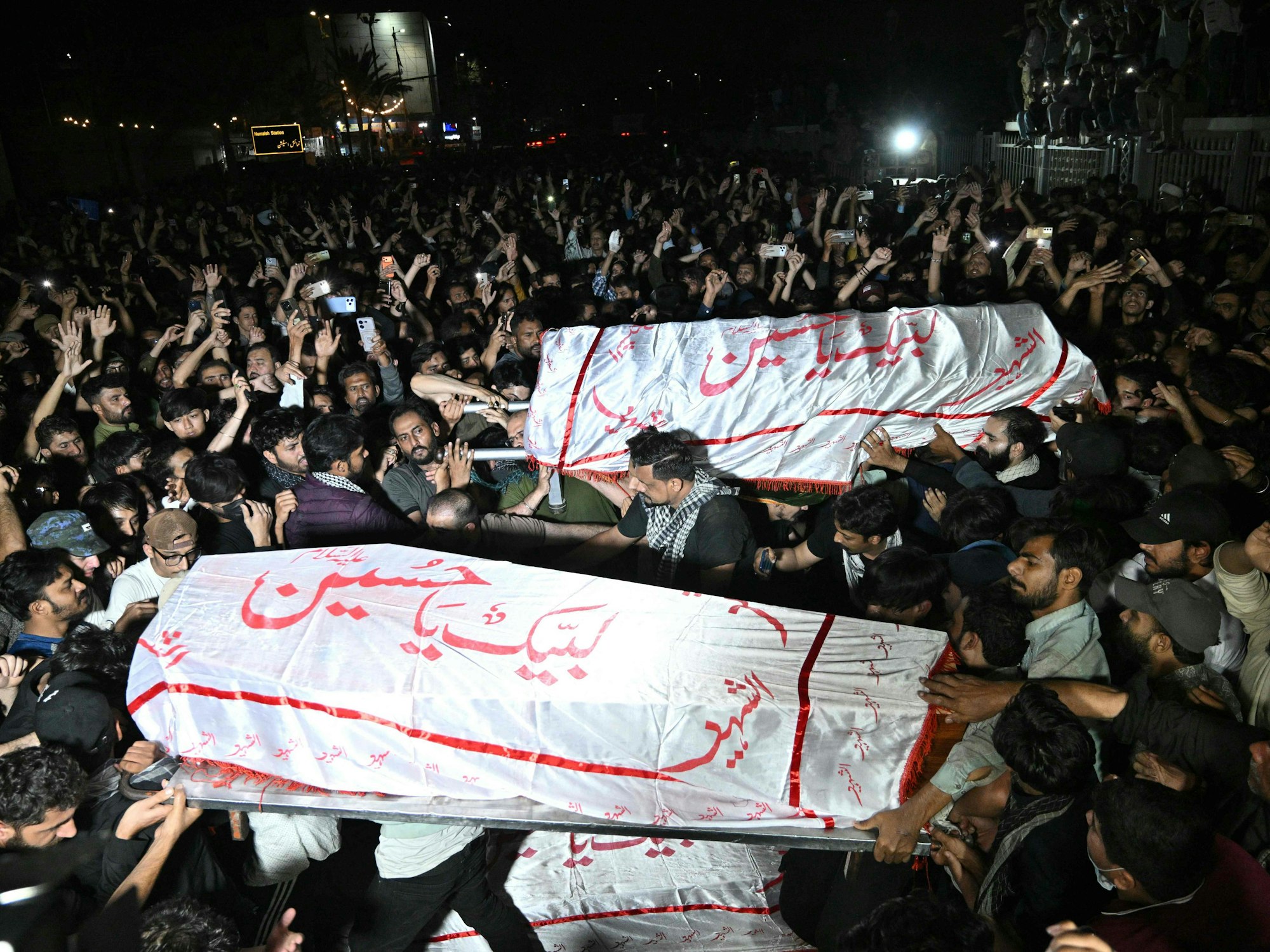Menschen tragen Särge durch Menschenmassen.