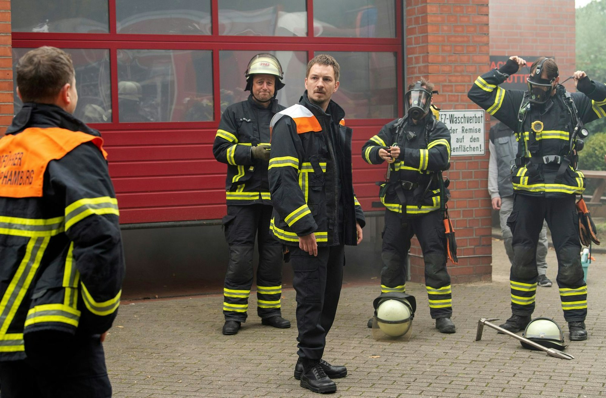 Feuerwehrmann Lars Herold (Johannes Kienast, dritter von links) kann nicht glauben, dass sein Chef Dennis Bruck (Mathis Reinhardt, links) plötzlich wieder auftaucht. (Bild: ARD / Thorsten Jander)