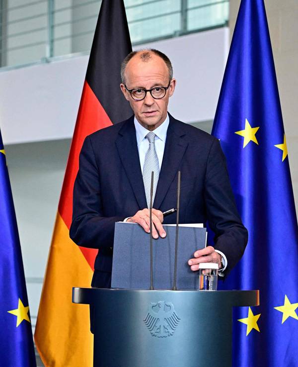 Bundeskanzler Friedrich Merz steht an einem Rednerpult, hinter sich jeweils zwei Deutschland- sowie EU-Fahnen.