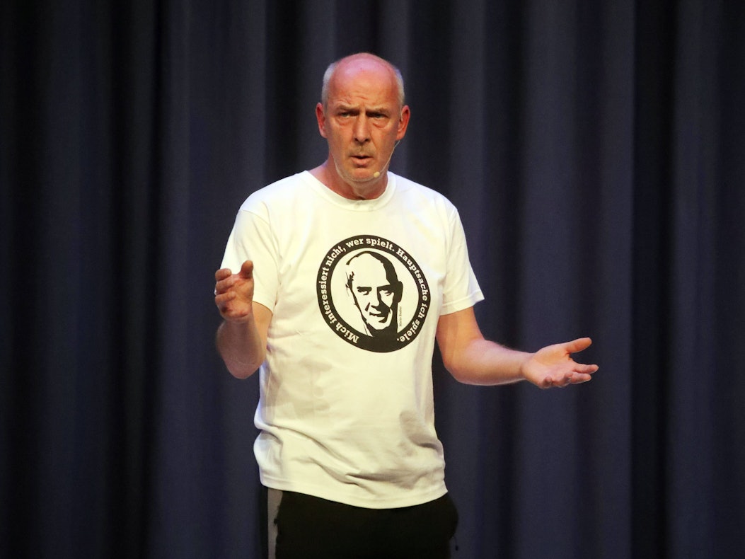 Mario Basler gestikuliert auf der Bühne.