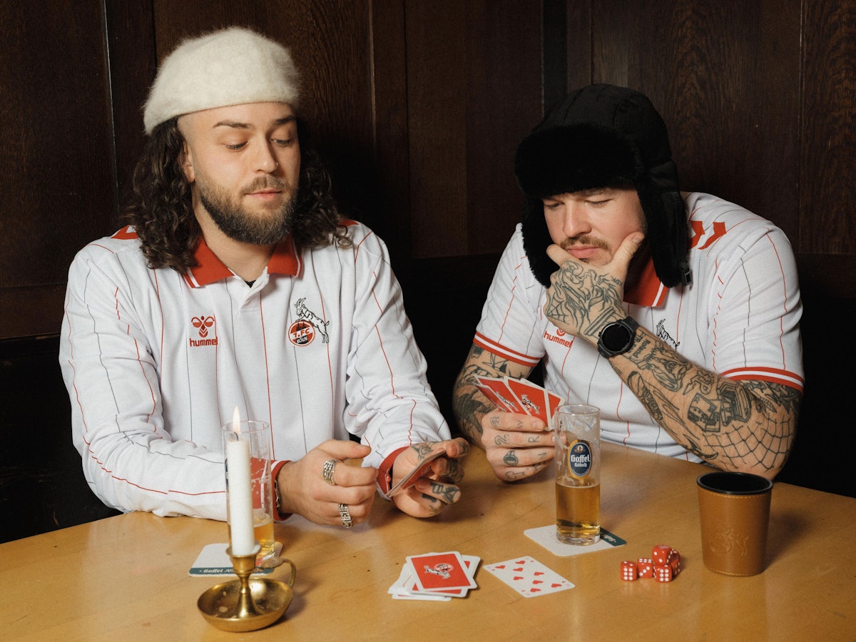 Zwei Models zeigen das neue Sondertrikot des 1. FC Köln in der Kneipe.