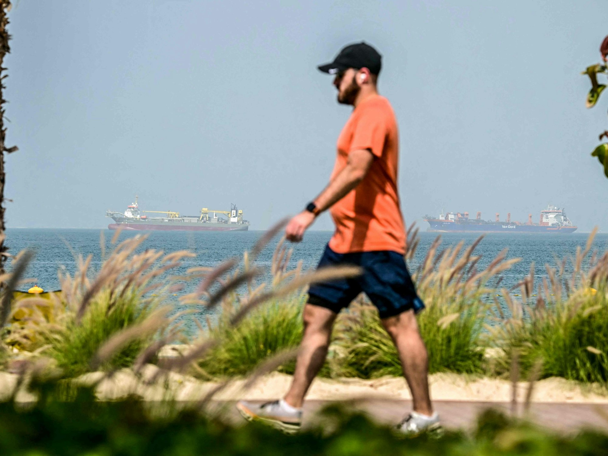 Dieser Mann geht gemütlich am Strand in Dubai spazieren.