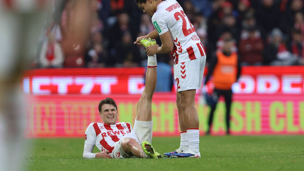 Joel Schmied (1. FC Köln) liegt verletzt am Boden, Jahmai Simpson-Pusey dehnt sein Bein.