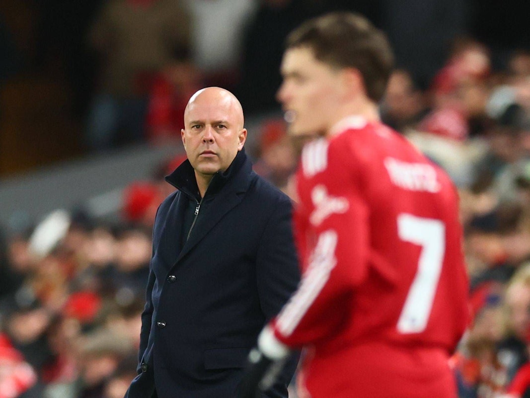 Arne Slot guckt vom Spielfeldrand Richtung Florian Wirtz. Der deutsche Fußballer ist auf dem Foto nur unscharf zu sehen.