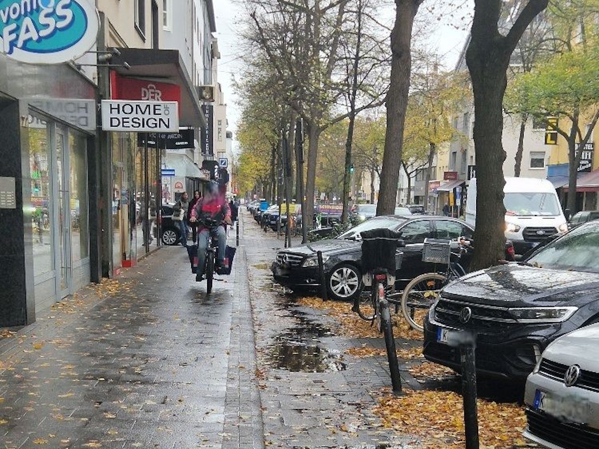 Ein Essenslieferant auf einem Fahrrad ist auf einem Gehweg unterwegs.