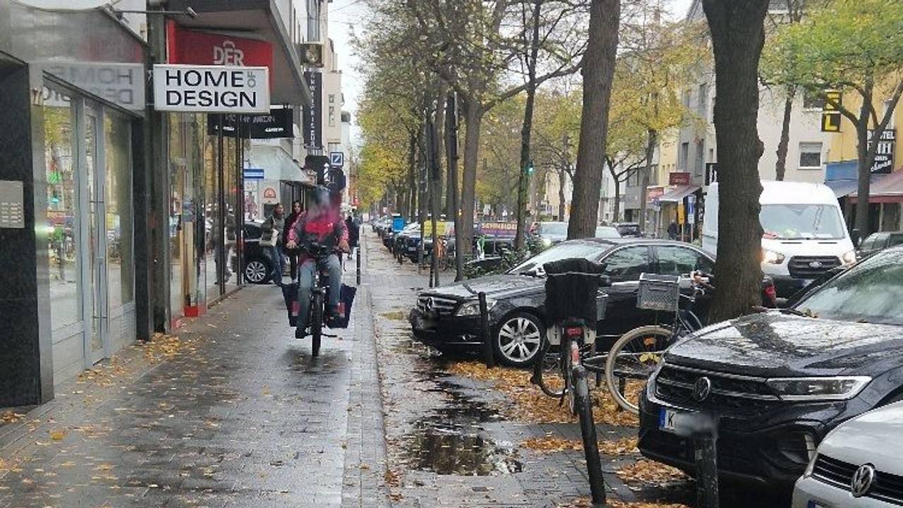 Ein Lieferdienstfahrer fährt auf dem Gehweg.