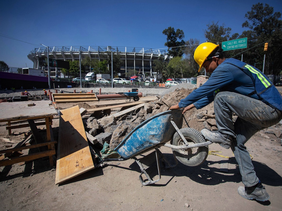 Vor dem Aztekenstadion in Mexiko-Stadt kämpft ein Bauarbeiter mit seiner Schubkarre.