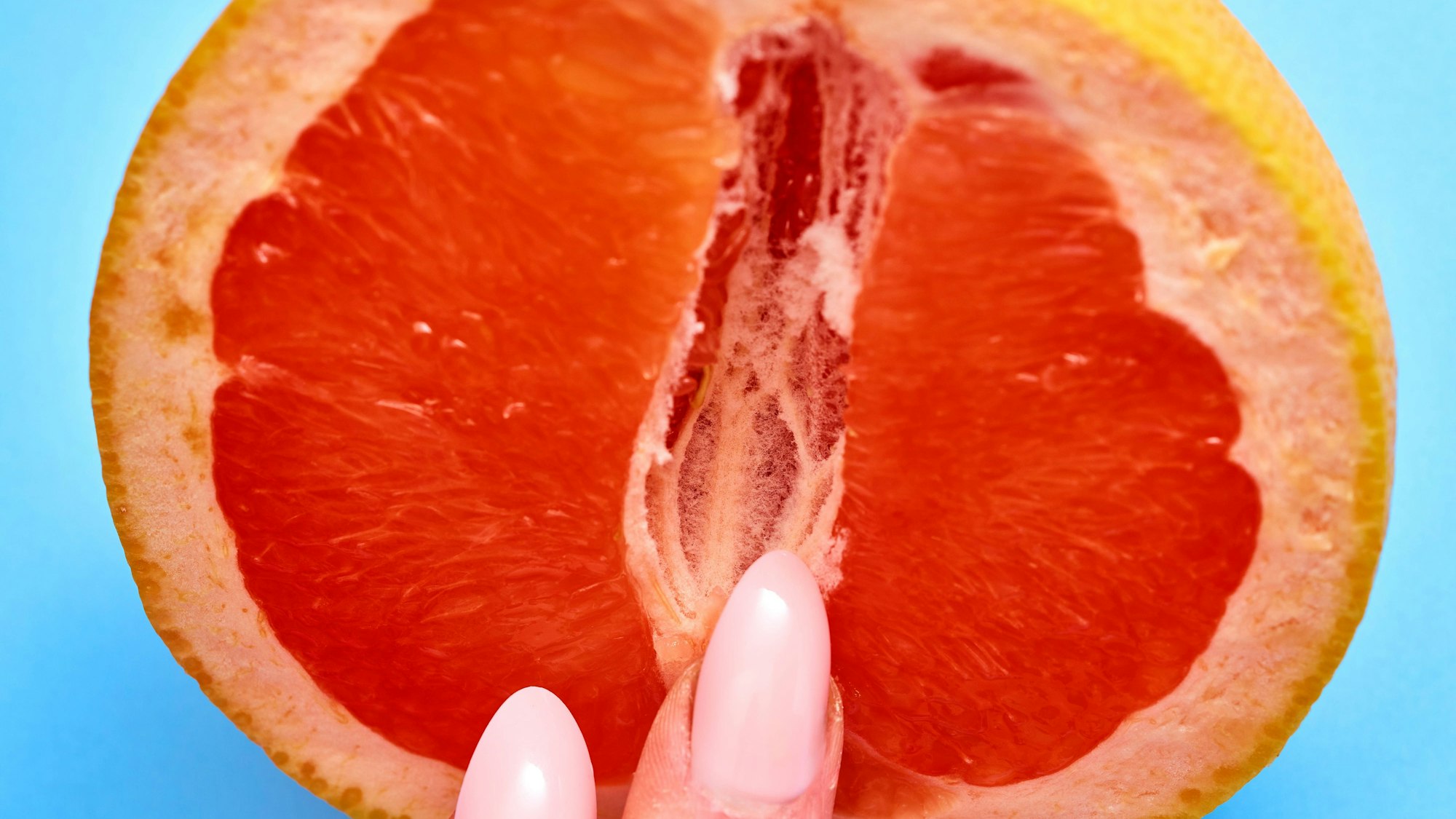 Bild von einer Blutorange mit Fingern.