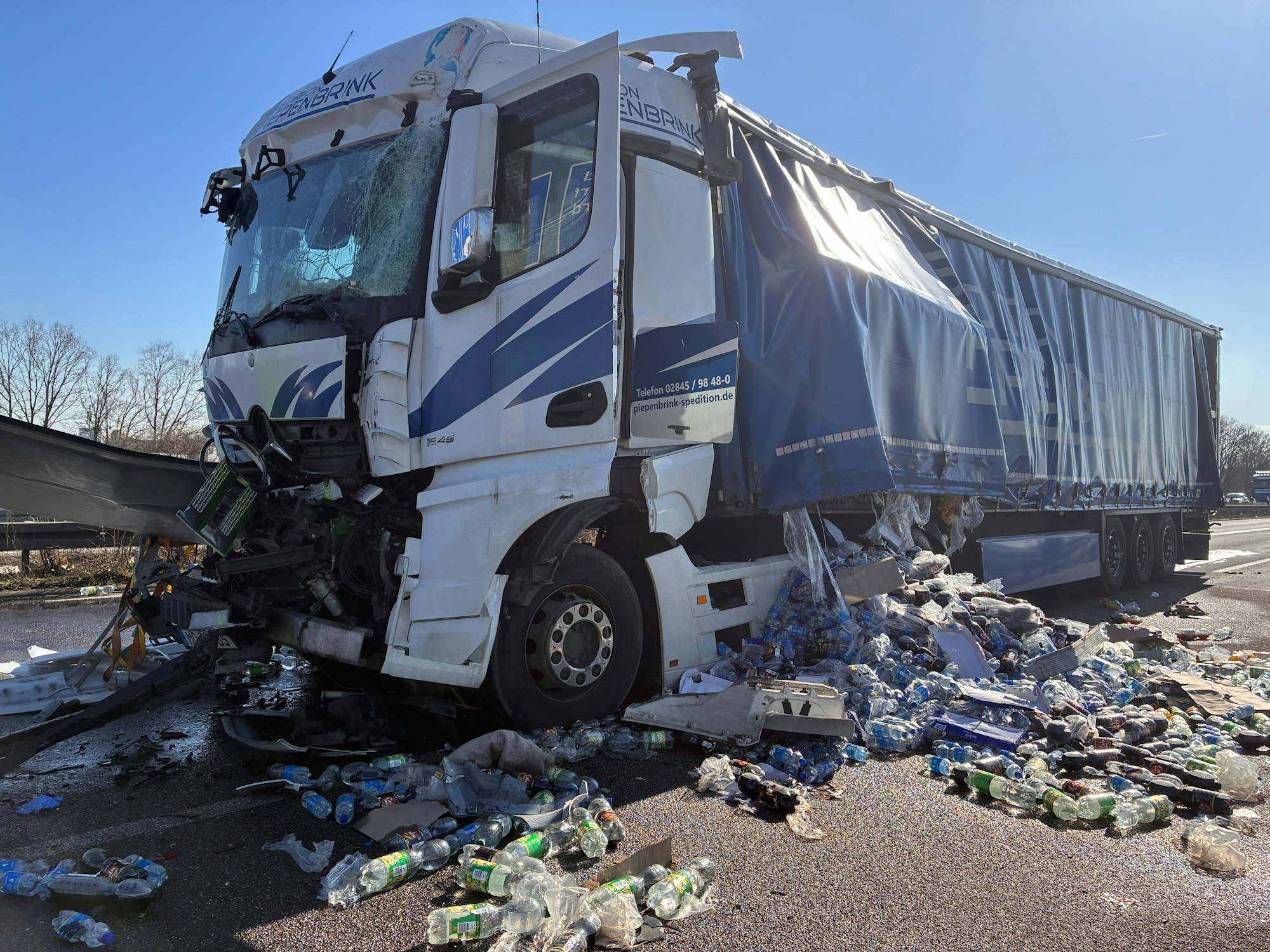 Ein beschädigter Lkw steht auf der Fahrbahn, er hat seine Ladung verloren. PET-Flaschen liegen um ihn herum.