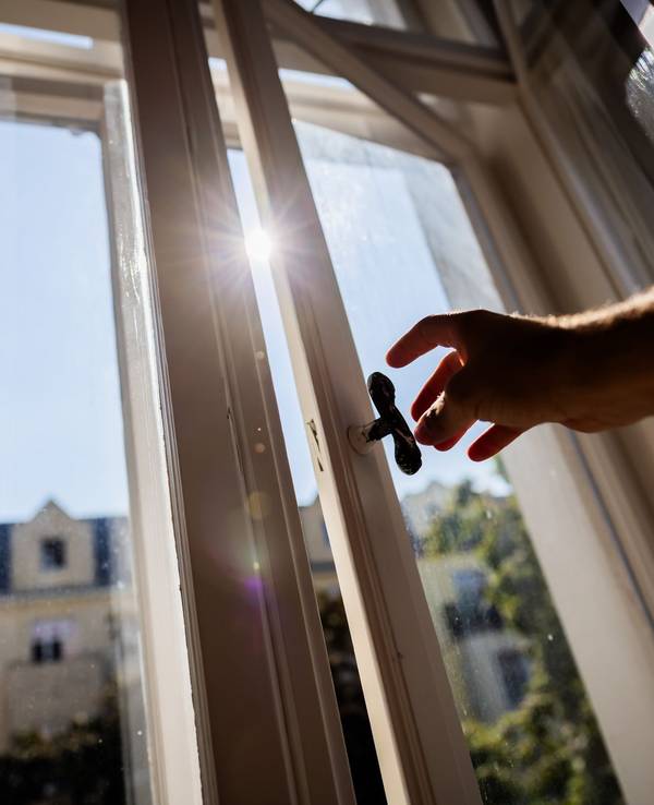 Eine Person öffnet in einer Berliner Wohnung ein Fenster