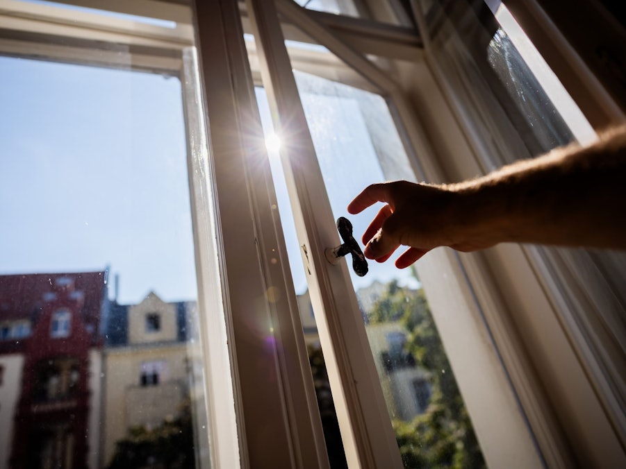 Eine Person öffnet in einer Berliner Wohnung ein Fenster