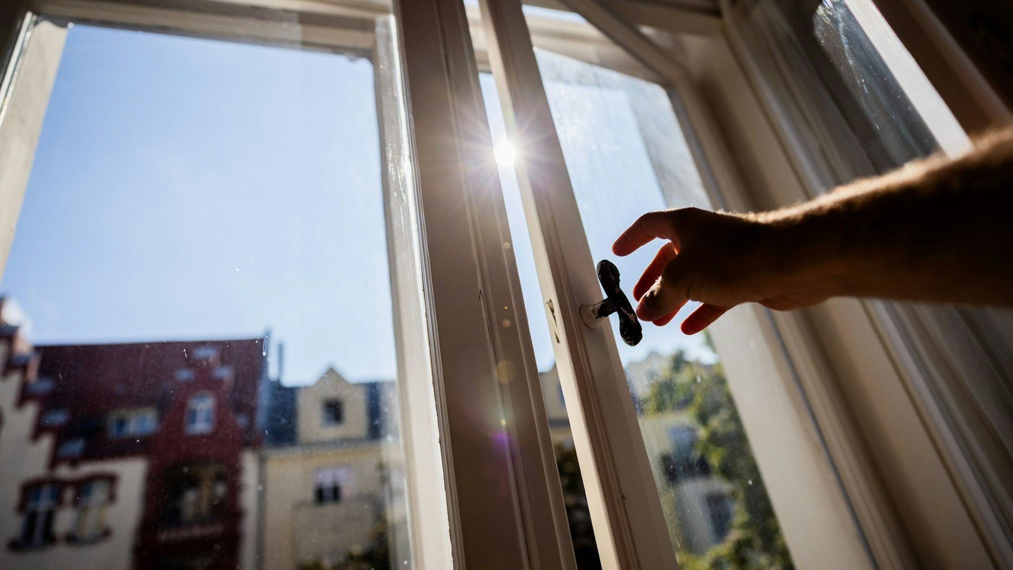 Eine Person öffnet in einer Berliner Wohnung ein Fenster