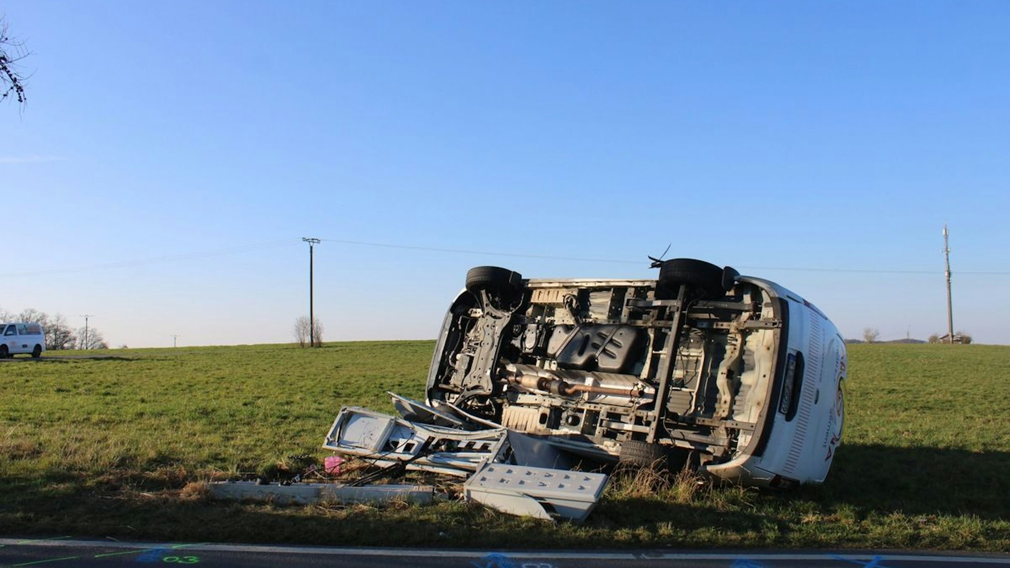 Ein umgekipptes Auto liegt nach einem Unfall auf einer Wiese.