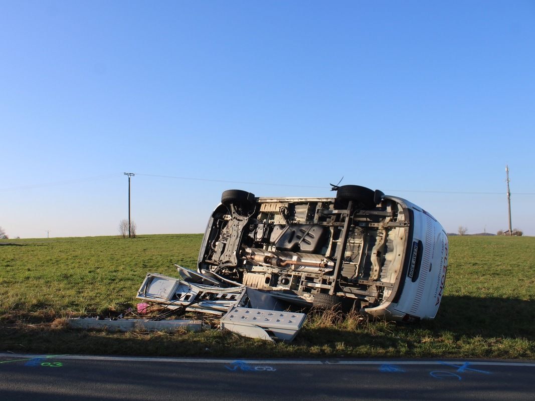 Ein umgekippter Van liegt nach einem Unfall auf einer Wiese.