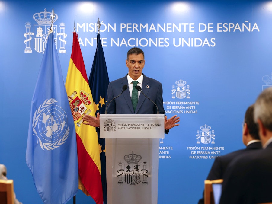 Pedro Sánchez spricht vor Fahnen und Text