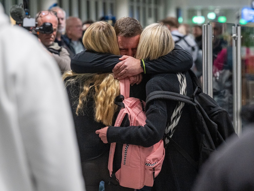 Ein Mann umarmt zwei Frauen.