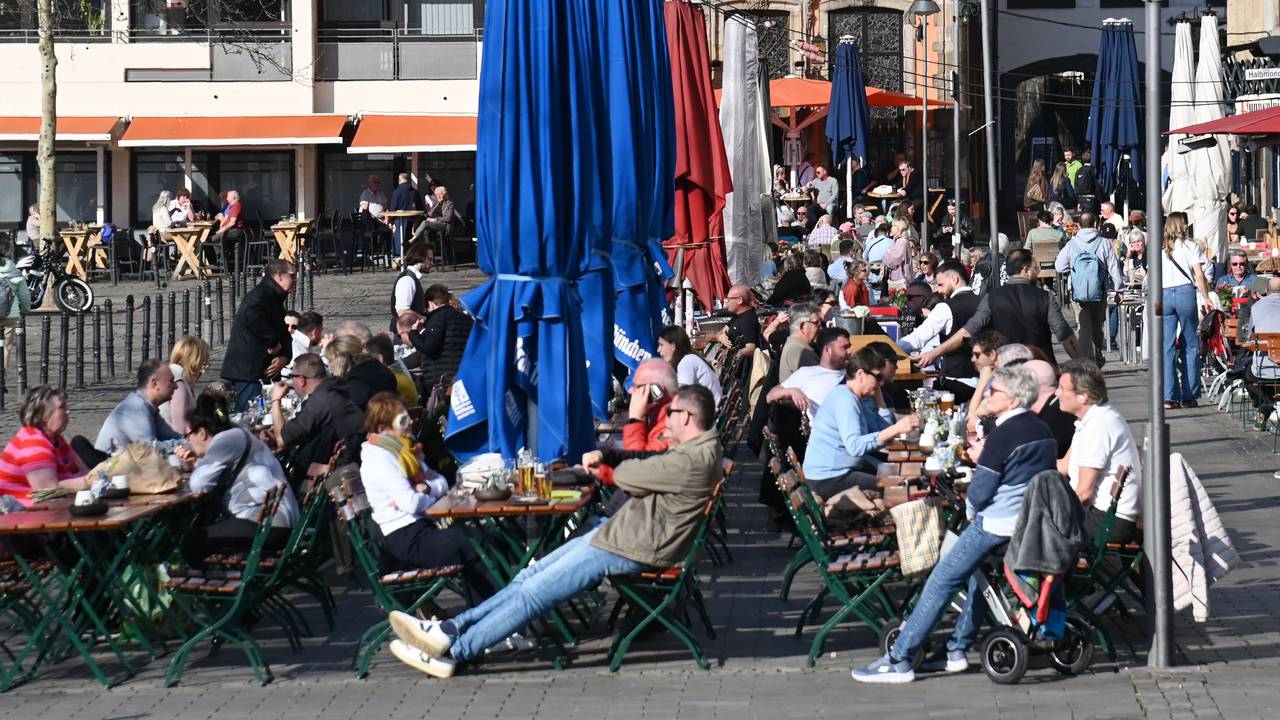 Menschen sitzen in einem Restaurant draußen und genießen die Sonne.