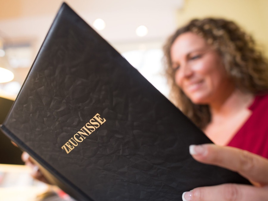 Frau liest in einer Mappe mit der Aufschrift «Zeugnisse»