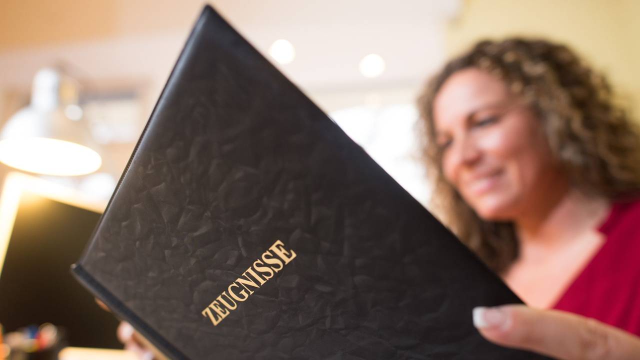 Frau liest in einer Mappe mit der Aufschrift «Zeugnisse»