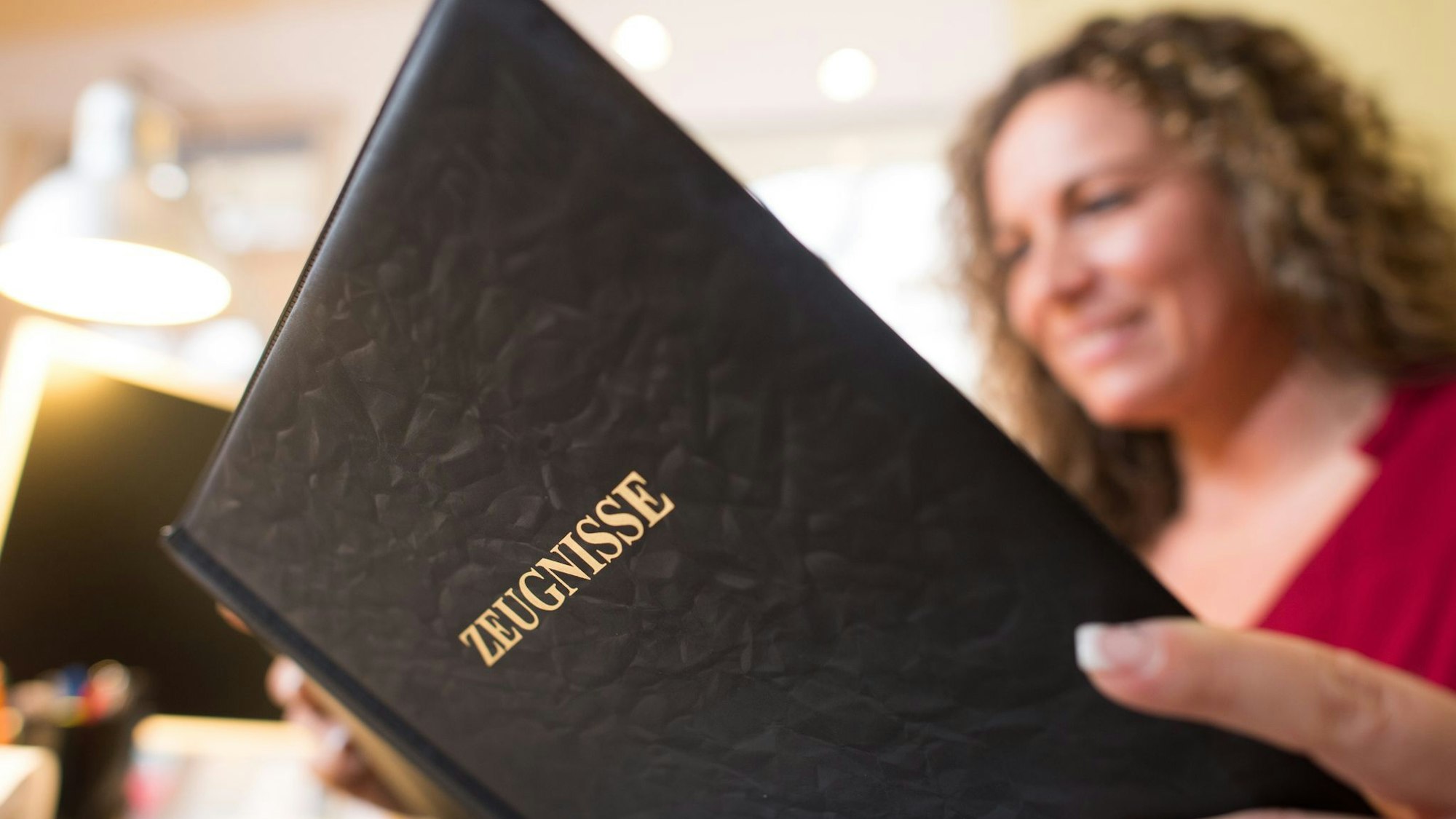 Frau liest in einer Mappe mit der Aufschrift «Zeugnisse»